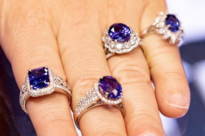 Hand wearing 4 sapphire and diamond rings