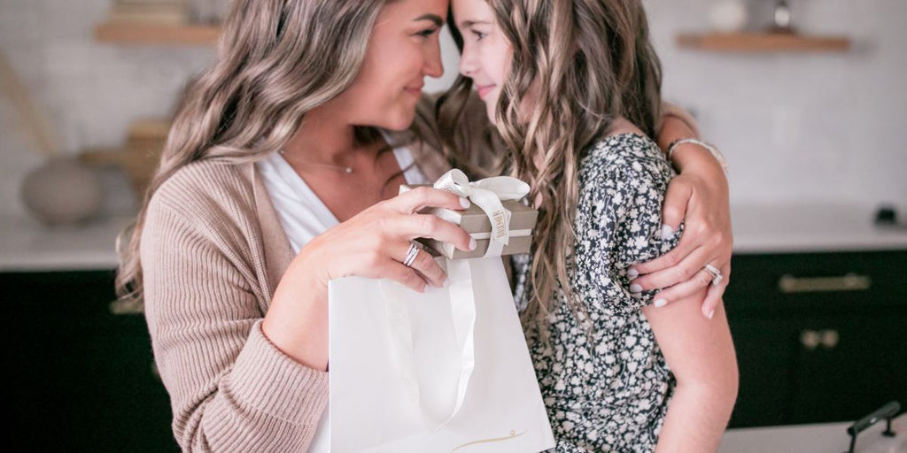 Mother and Daughter Embracing while Opening a Bremer Gift Box