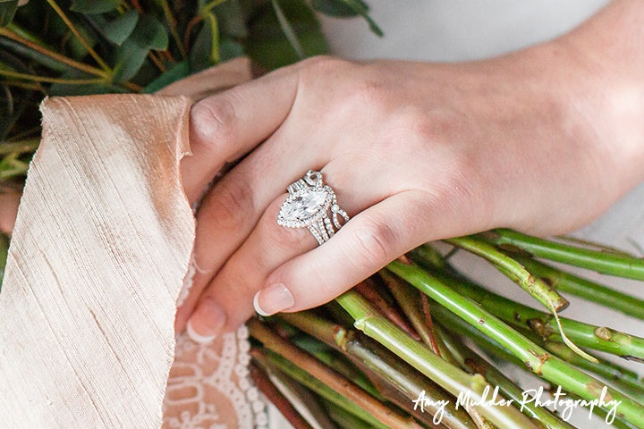 Hand wearing diamond engagement ring holding bouquet of flowers