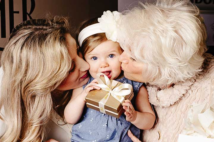 Baby girl being kissed on the cheek by mother and grandmother
