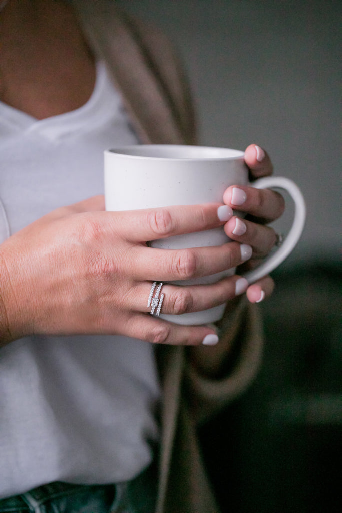 Fashion ring on finger of hand holding coffee mug